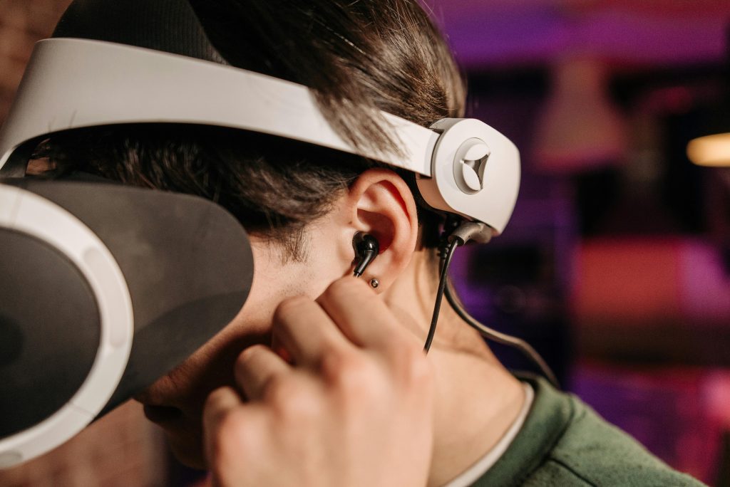 A Person in Green Shirt Using VR Goggles Using Black Headphones